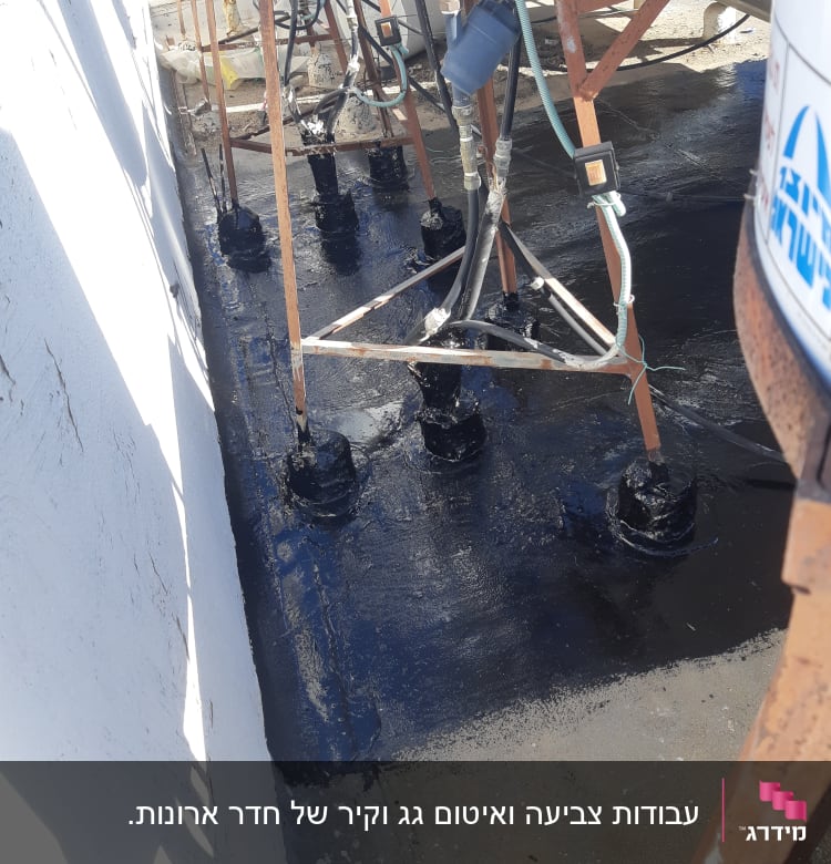 איטום גג עם חומר שחור סביב צינורות מתכת